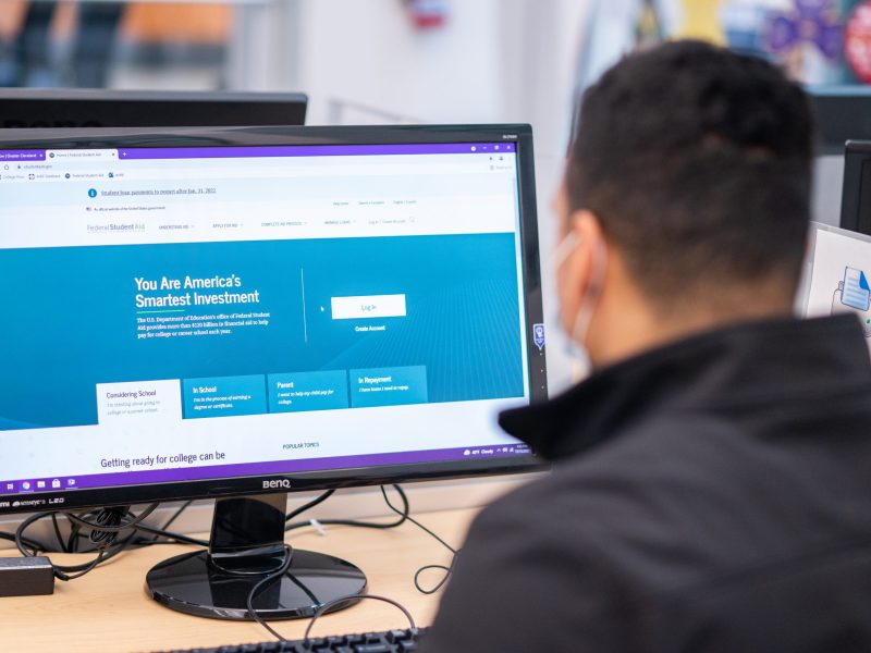 A student sits at a computer, looking at a federal financial aid website.
