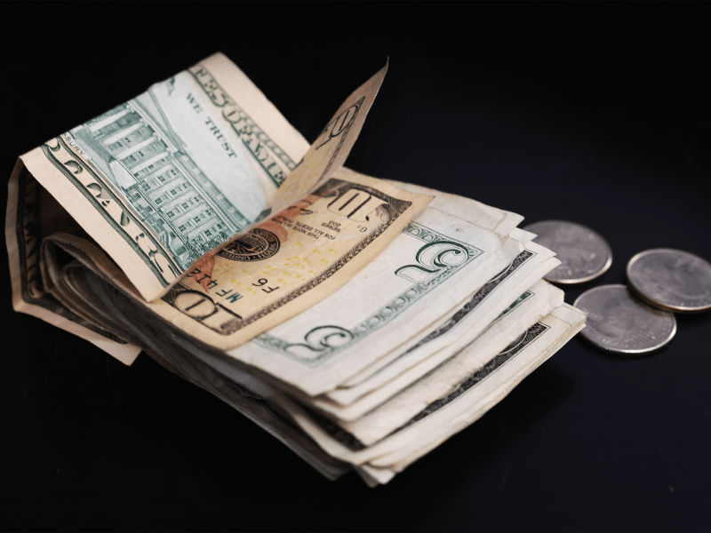 Phot of folded $10 and $5 bills with three quarters.